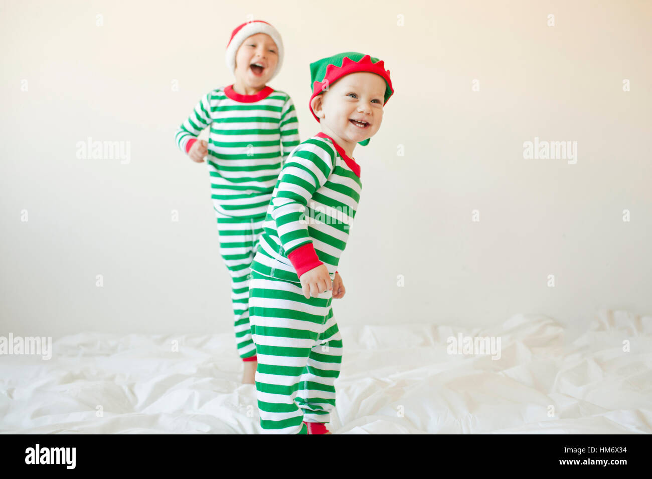 Glückliches Baby Boys stehen auf Bett vor weißem Hintergrund Stockfoto