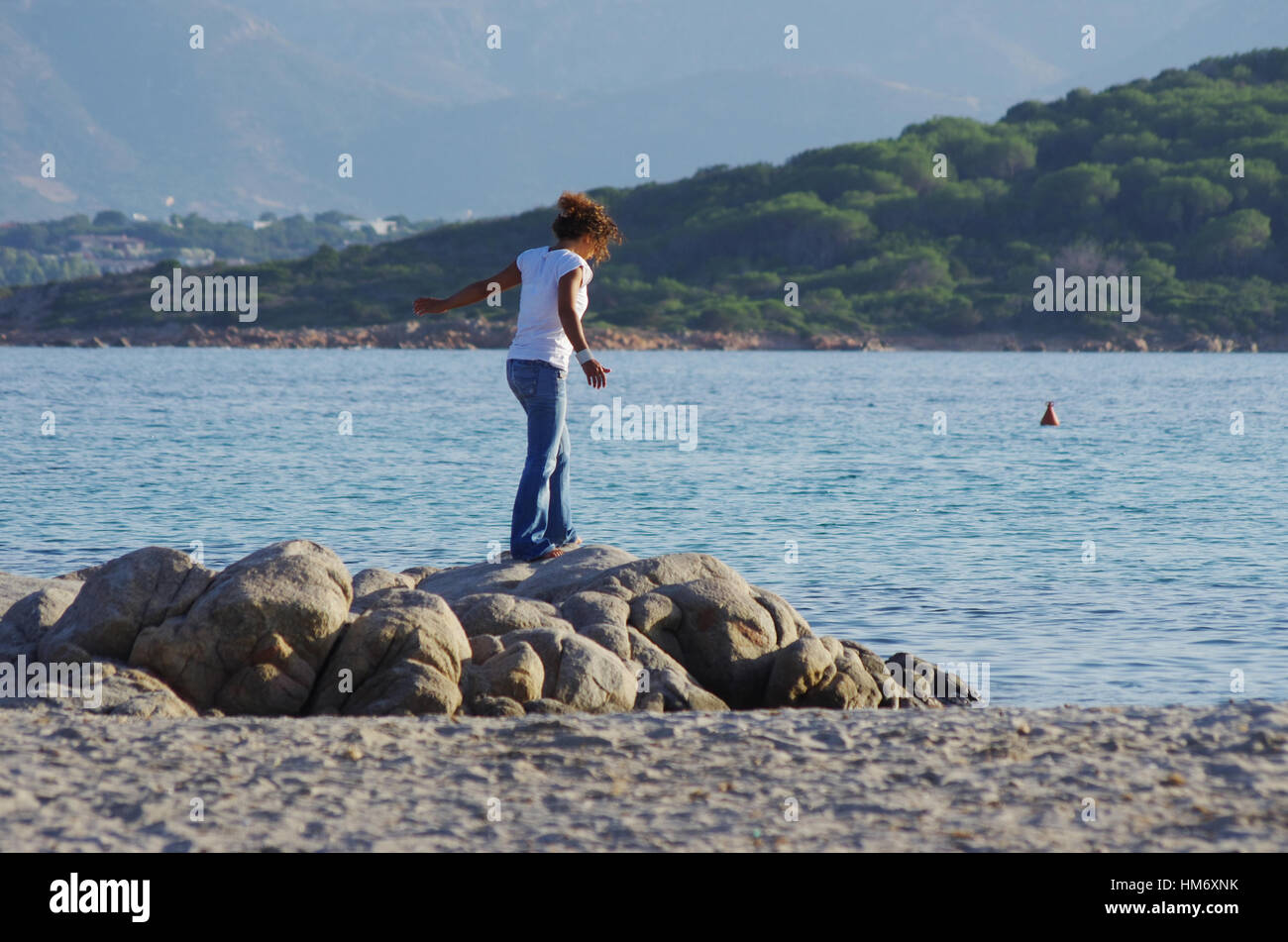 Junge Frau zu Fuß auf einem Felsen an der Küste Stockfoto