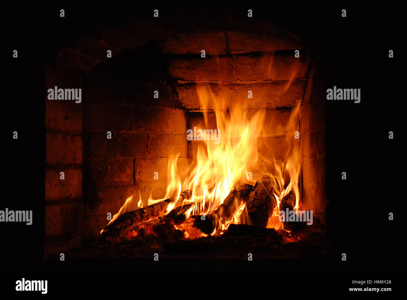 Holzscheite brennen in den gemauerten Kamin Stockfoto