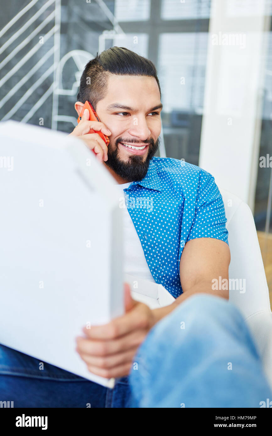 Junger Student tätigen eines Anrufs als Kommunikation Intern in Start-up Stockfoto