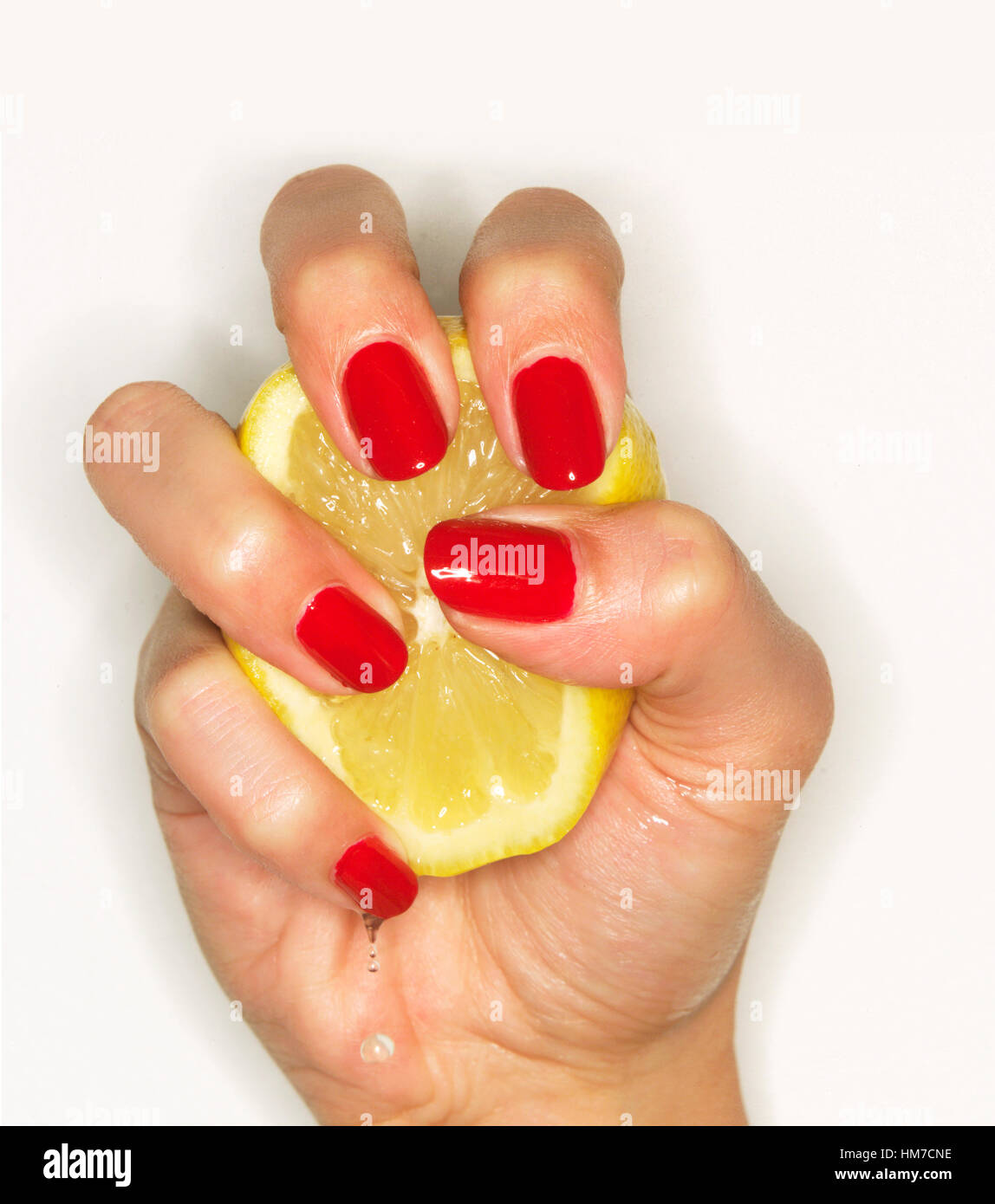Hand der Frau mit rotem Nagellack Zitrone auspressen Stockfoto