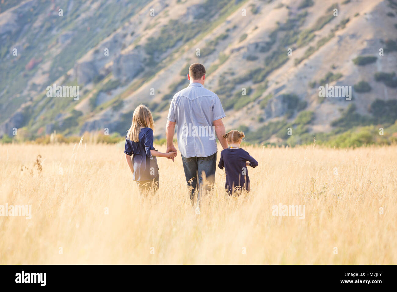 Vater mit zwei Töchtern (4-5, 8-9) zu Fuß in Feld Stockfoto