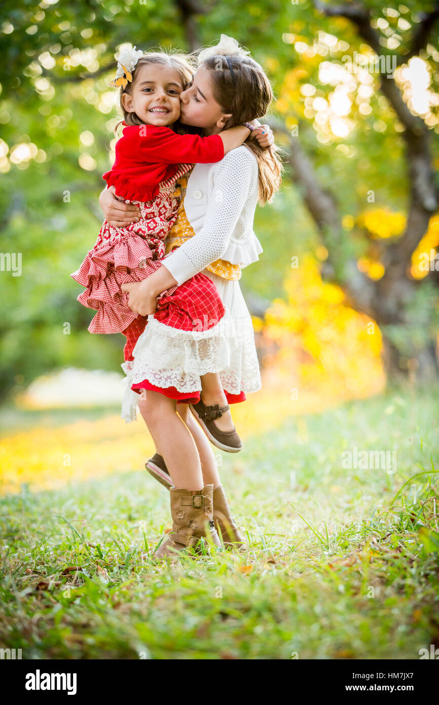 Mädchen halten und Schwester im Kirschgarten zu küssen Stockfoto