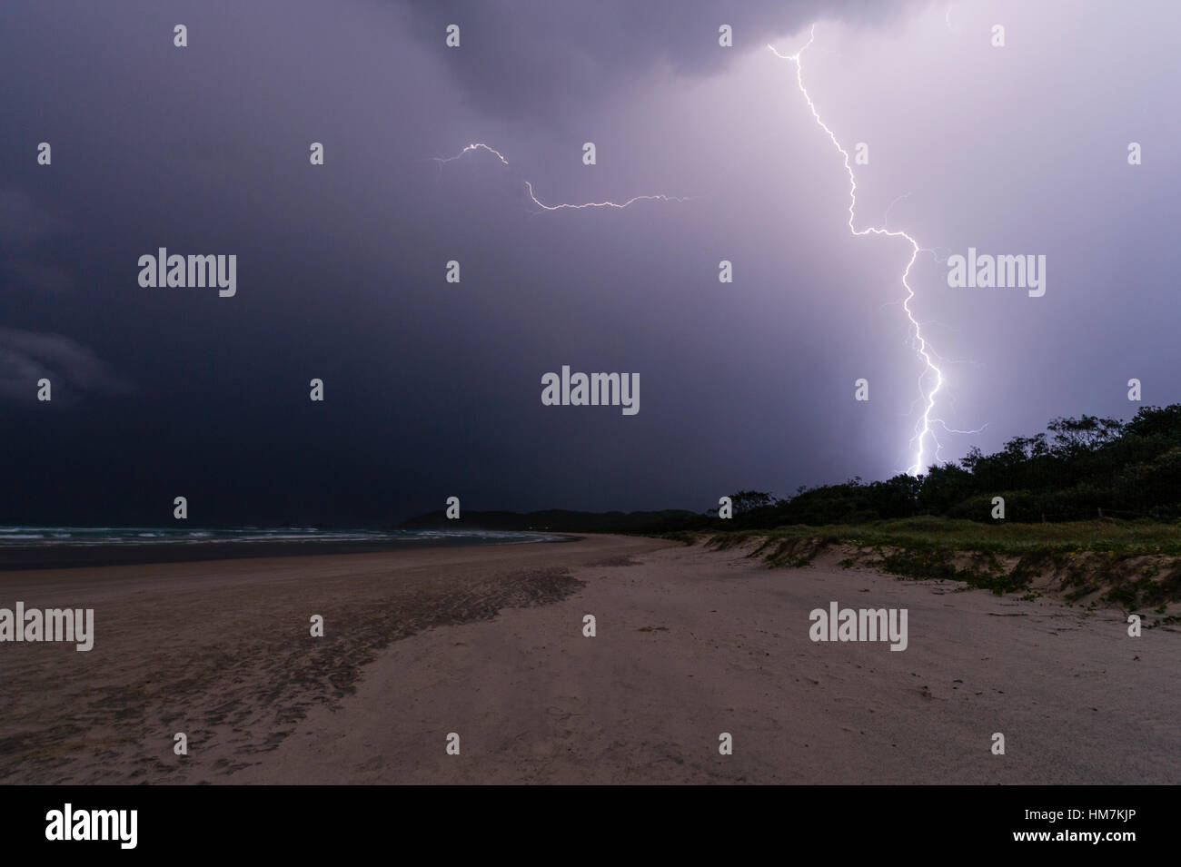 Blitz schlägt eine Sanddüne und das Meer während eines Gewitters. Stockfoto