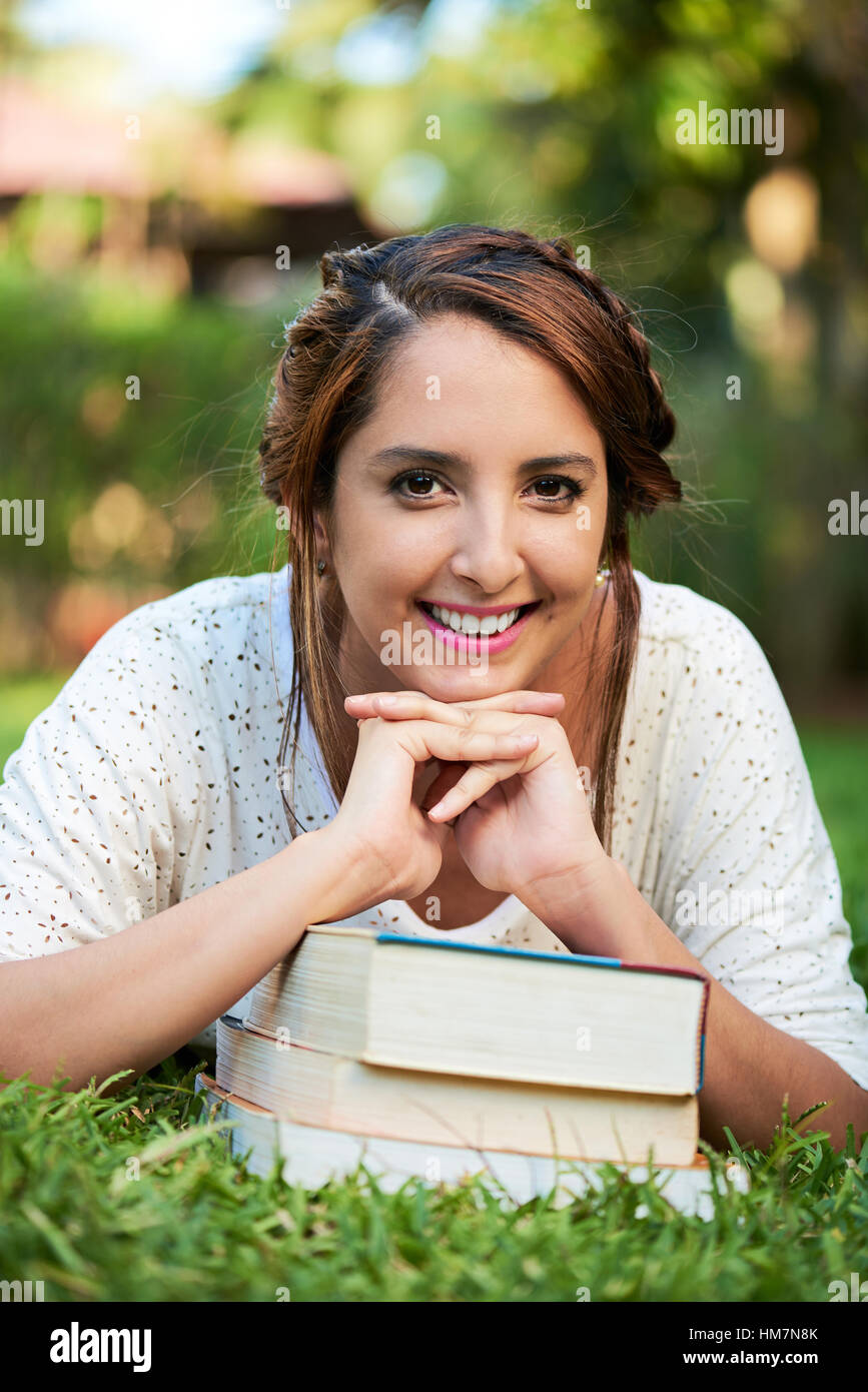 Stütze dich auf lächelndes Mädchen Bücher im Park Rasen Stockfoto
