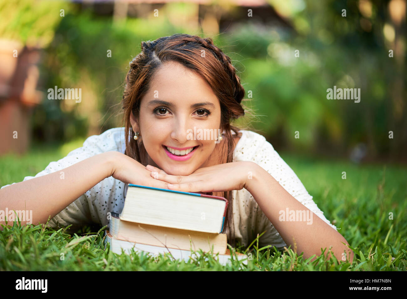 Mädchen ruhen auf Bücher und lächelnd im park Stockfoto