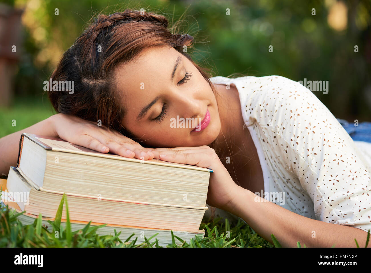 Mädchen schlafend auf Bücher im park Stockfoto