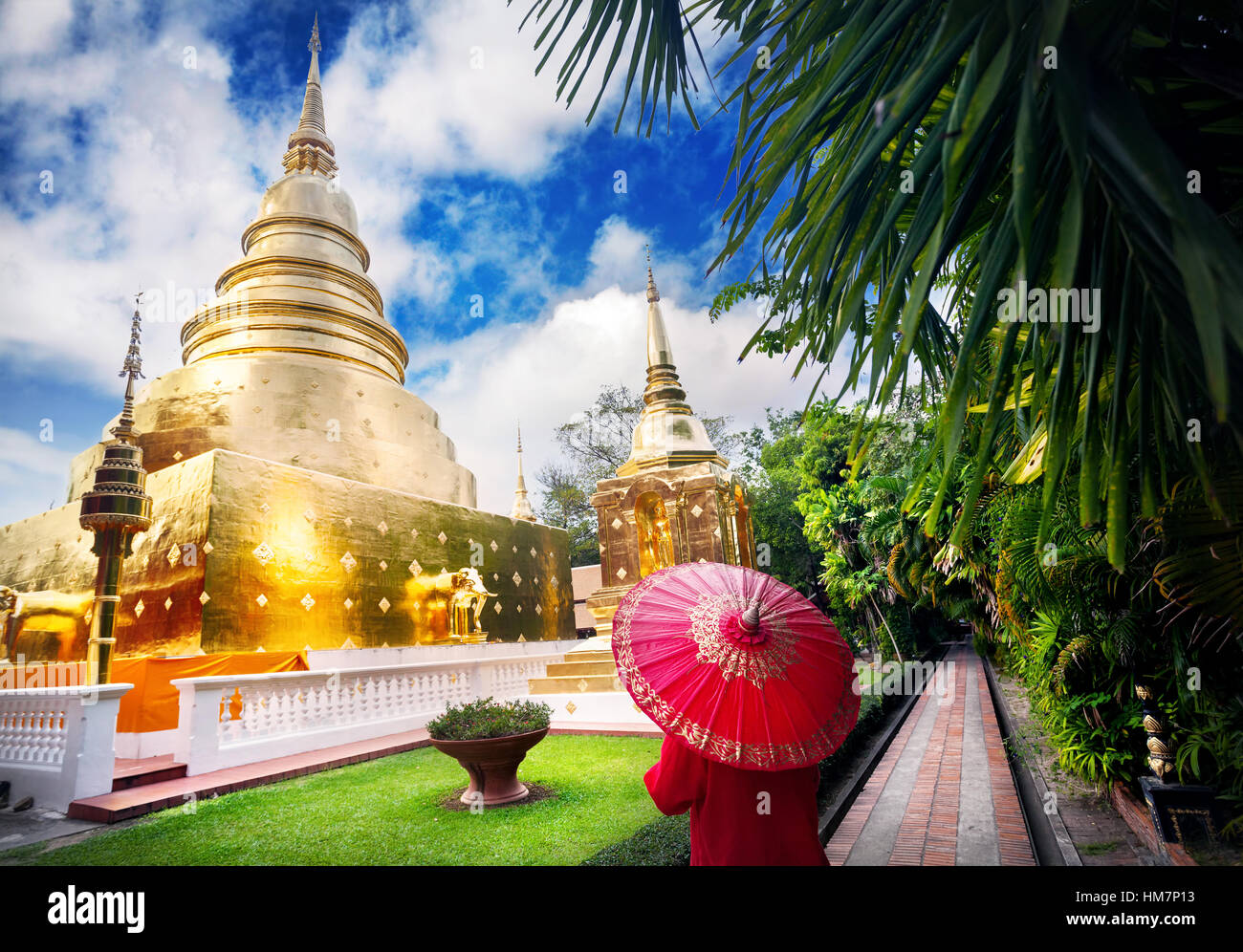 Frau Tourist mit roten traditionelle Thai Regenschirm in der Nähe von goldenen Stupa im Tempel Wat Phra Singh in Chiang Mai, Thailand Stockfoto