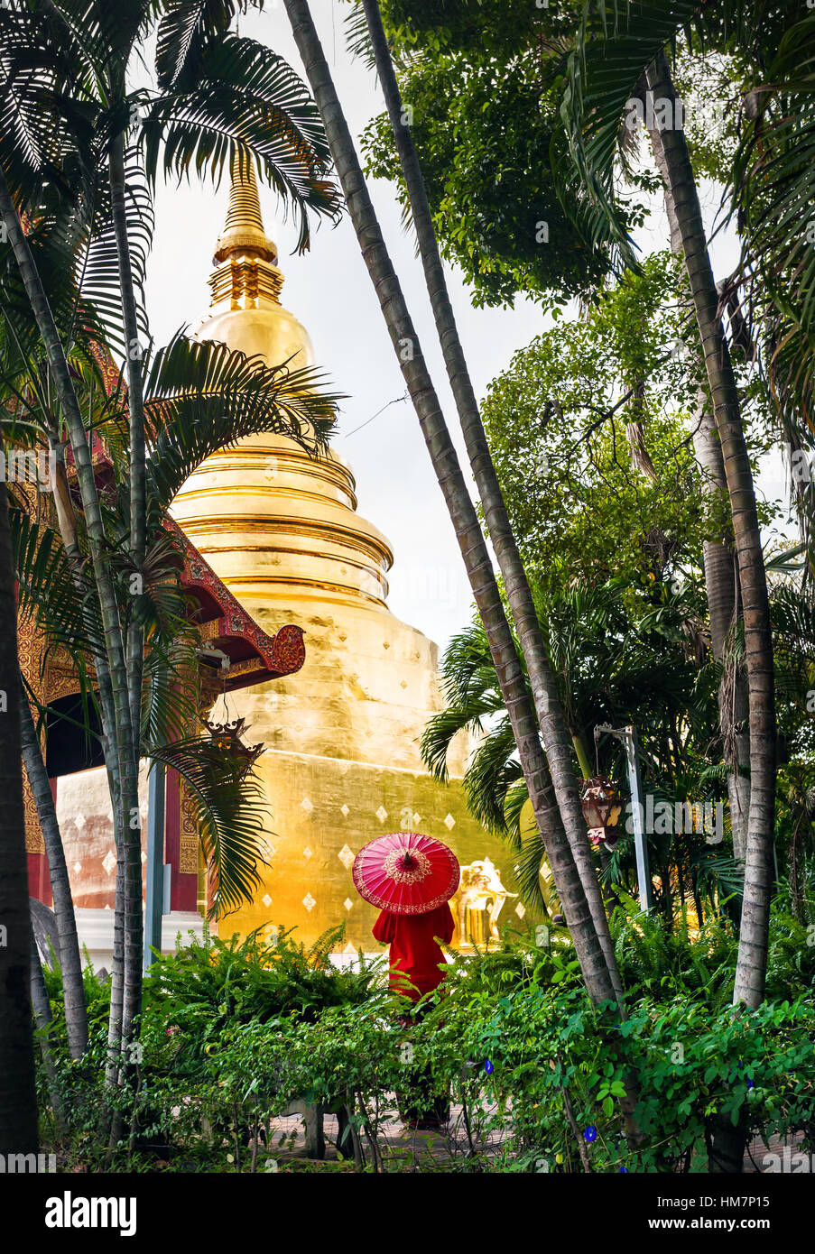 Frau Tourist mit roten traditionelle Thai Regenschirm in der Nähe von goldenen Stupa Tempel Wat Phra Singh in der Nähe von tropischen Bambusgarten in Chiang Mai, Thailand Stockfoto