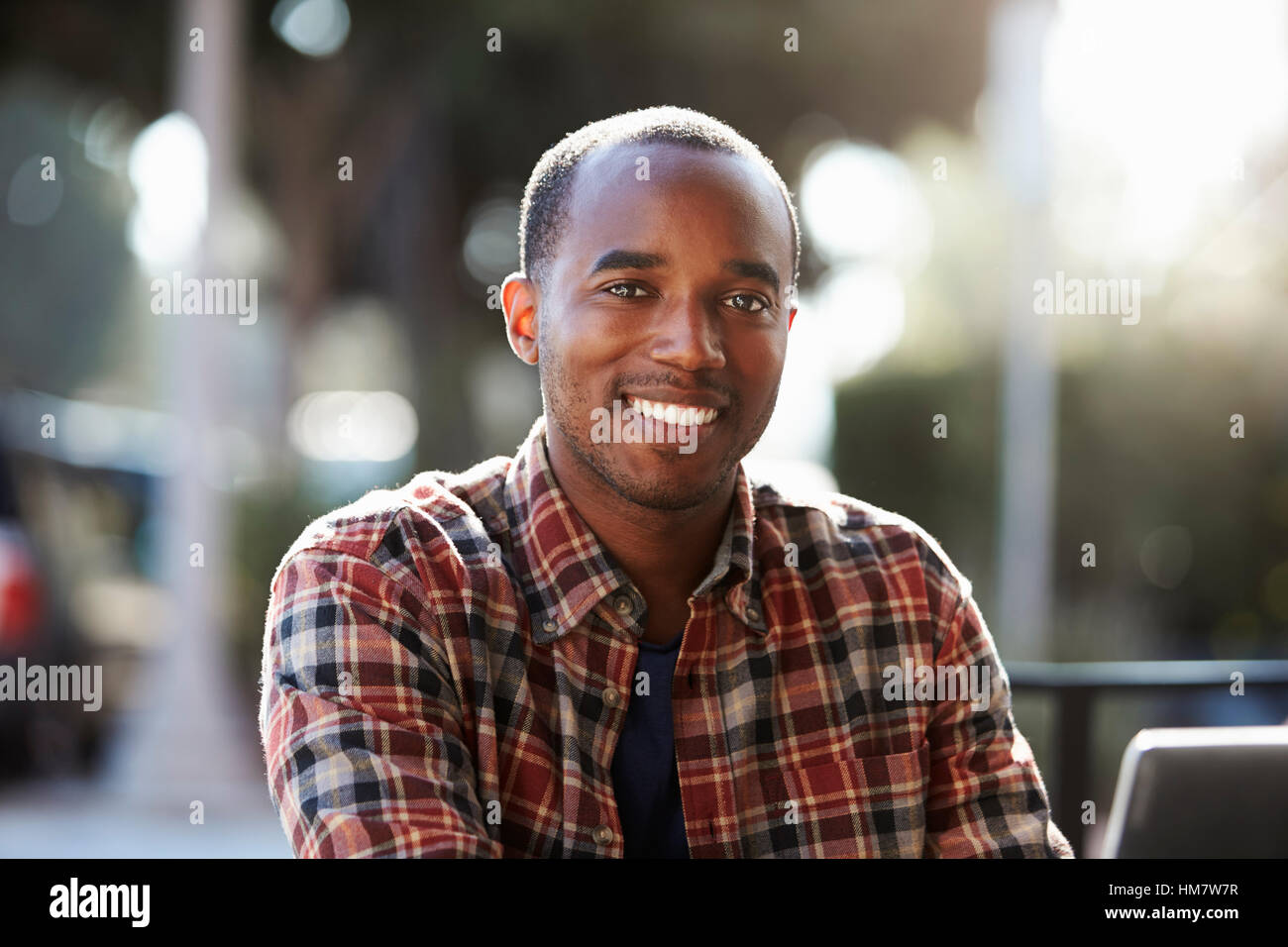 Junge schwarze Mann sitzt im Freien, Porträt Stockfoto