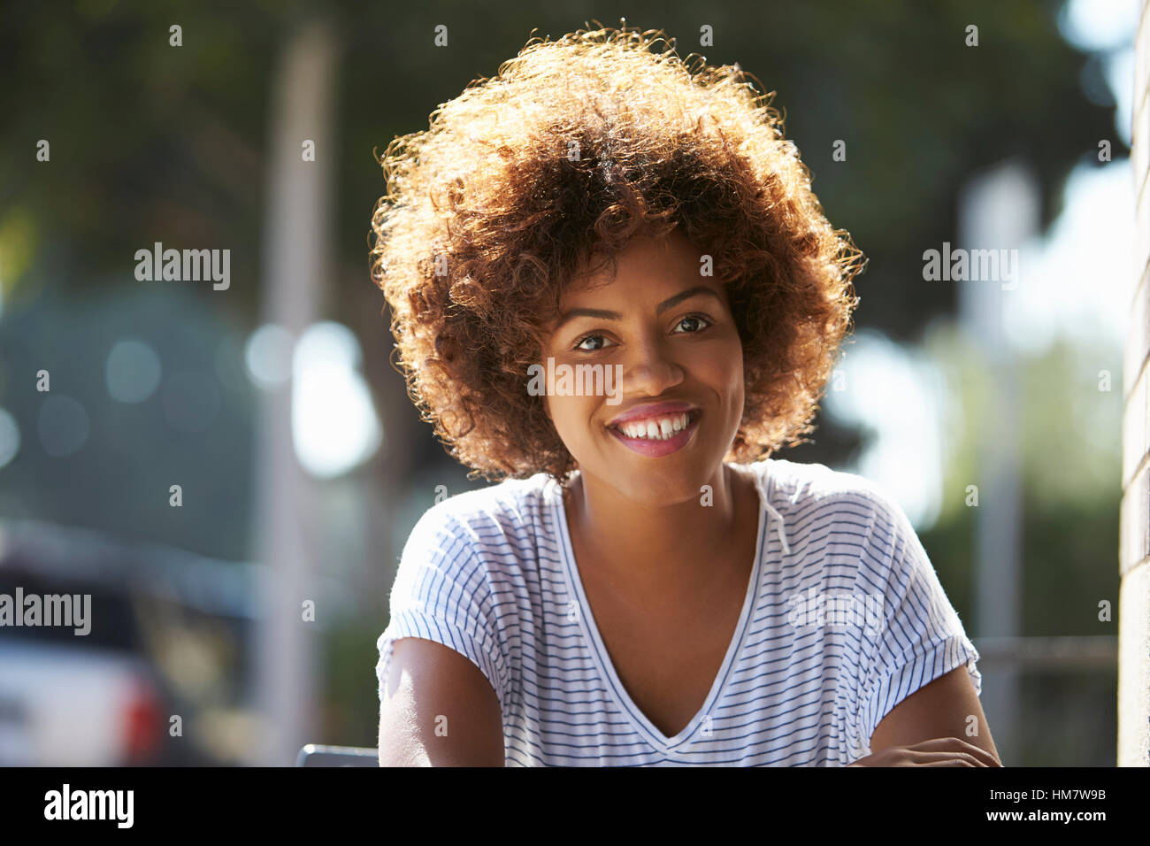 Porträt der glückliche junge schwarze Frau sitzen im freien Stockfoto