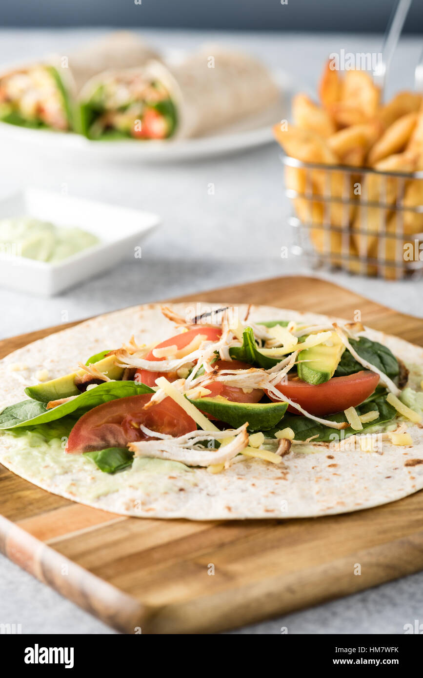 Gegrilltes Hühnerfleisch wraps mit Karotte, Käse, Avocado und Spinat. Mit Pommes Frites auf der Seite. Stockfoto