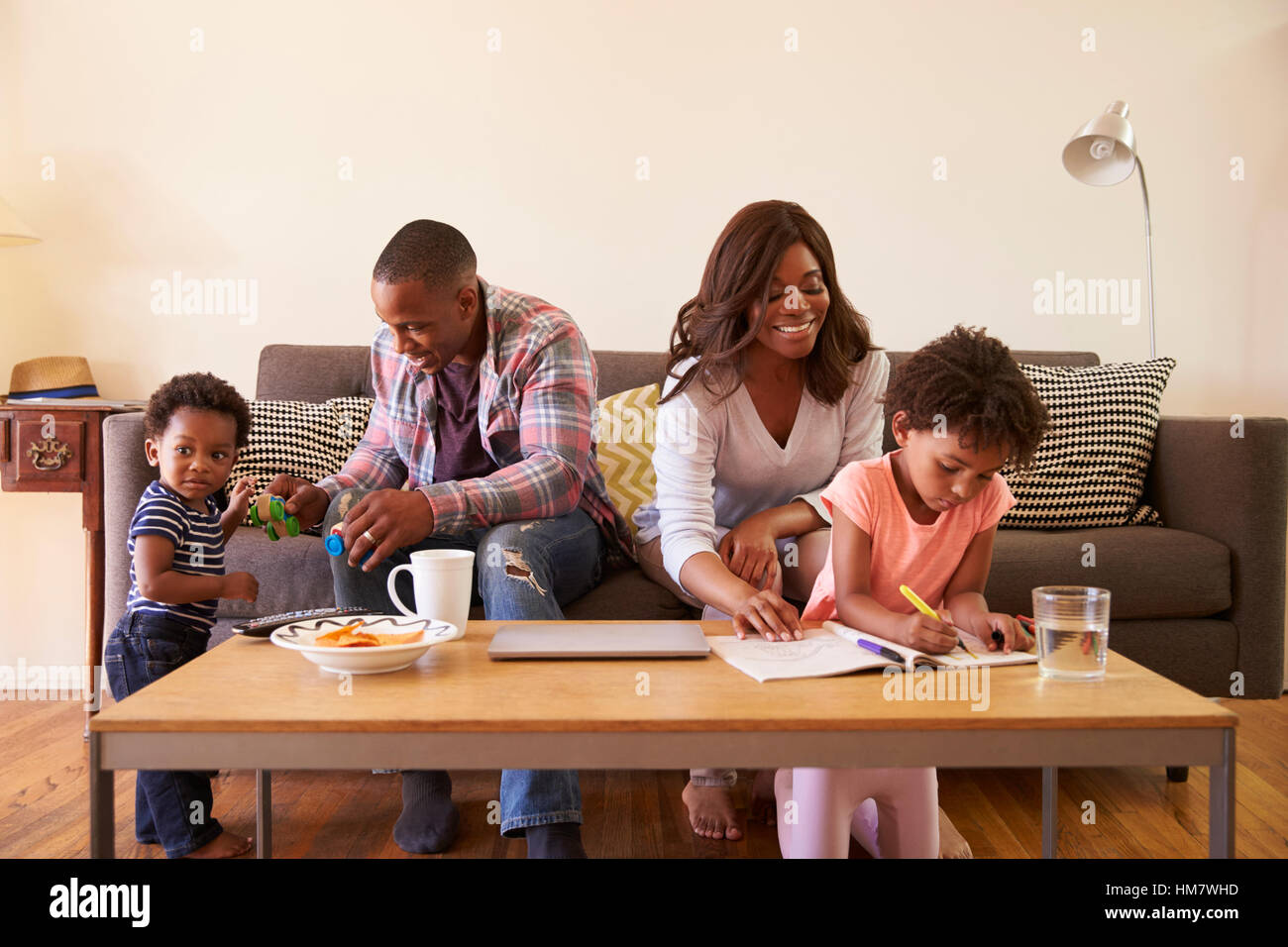 Familie auf Sofa sitzen, wie Tochter In Bilderbuch Farben Stockfoto