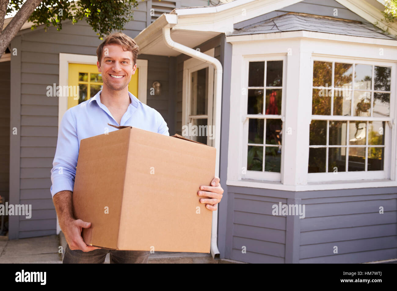 Mann trägt Box in neues Zuhause am Umzugstag Stockfoto