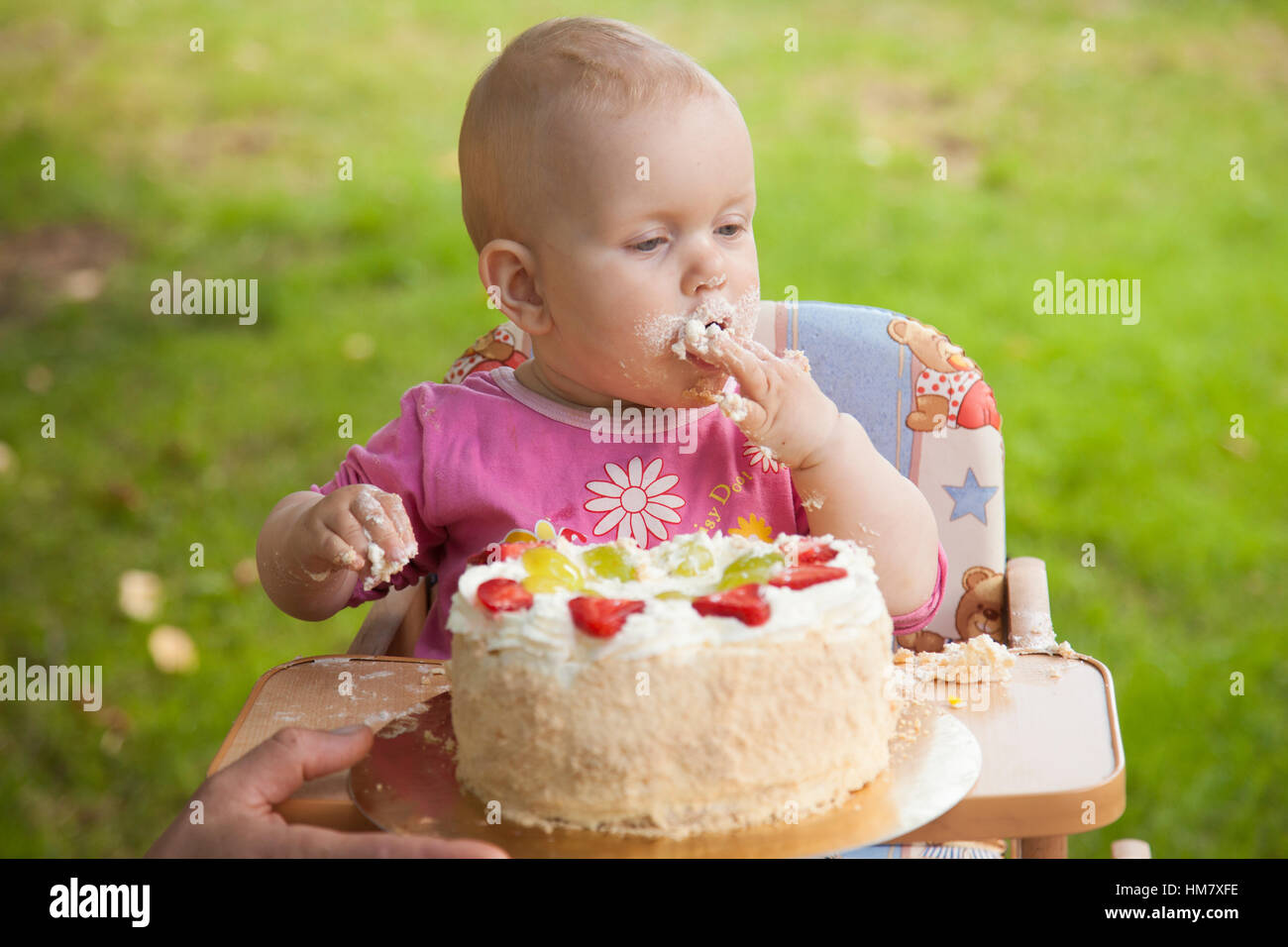 Ein Baby Essen Geburtstagskuchen mit seinen Händen Stockfoto