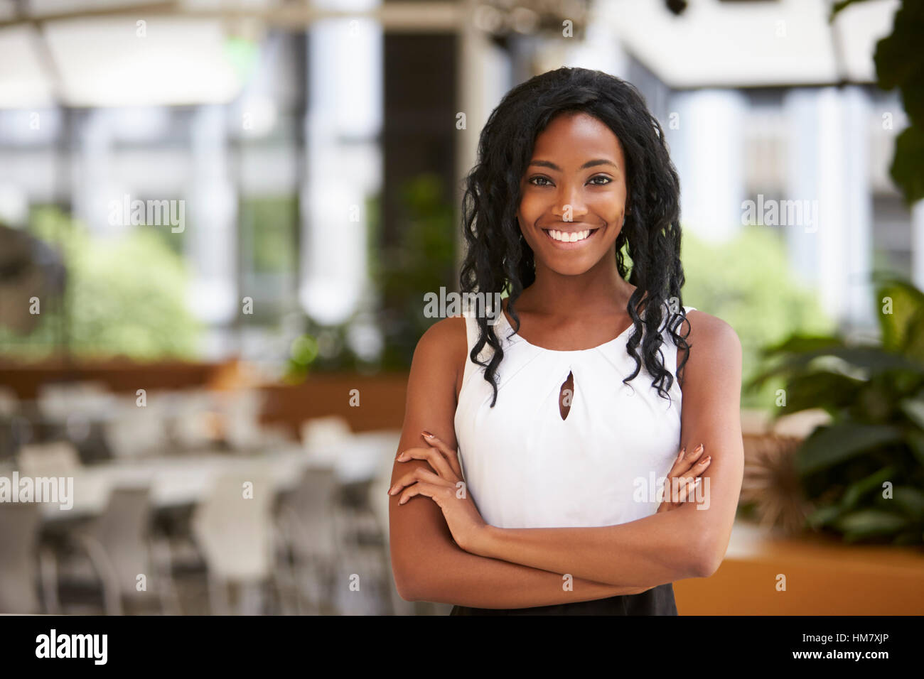 Lächelnde junge schwarze Geschäftsfrau mit Arme gekreuzt Stockfoto