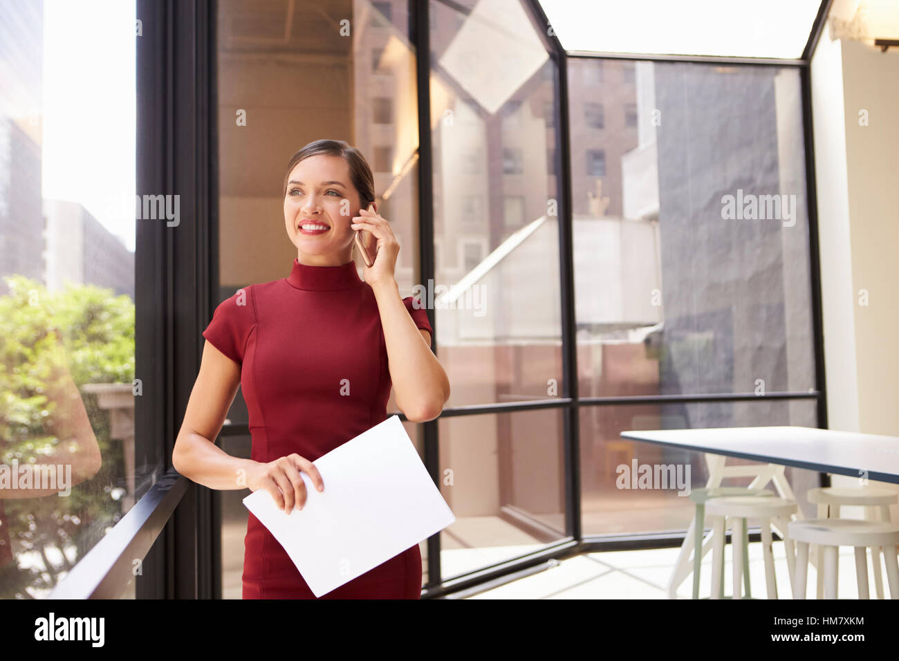 Lächelnde junge weiße Geschäftsfrau auf Handy im modernen Büro Stockfoto