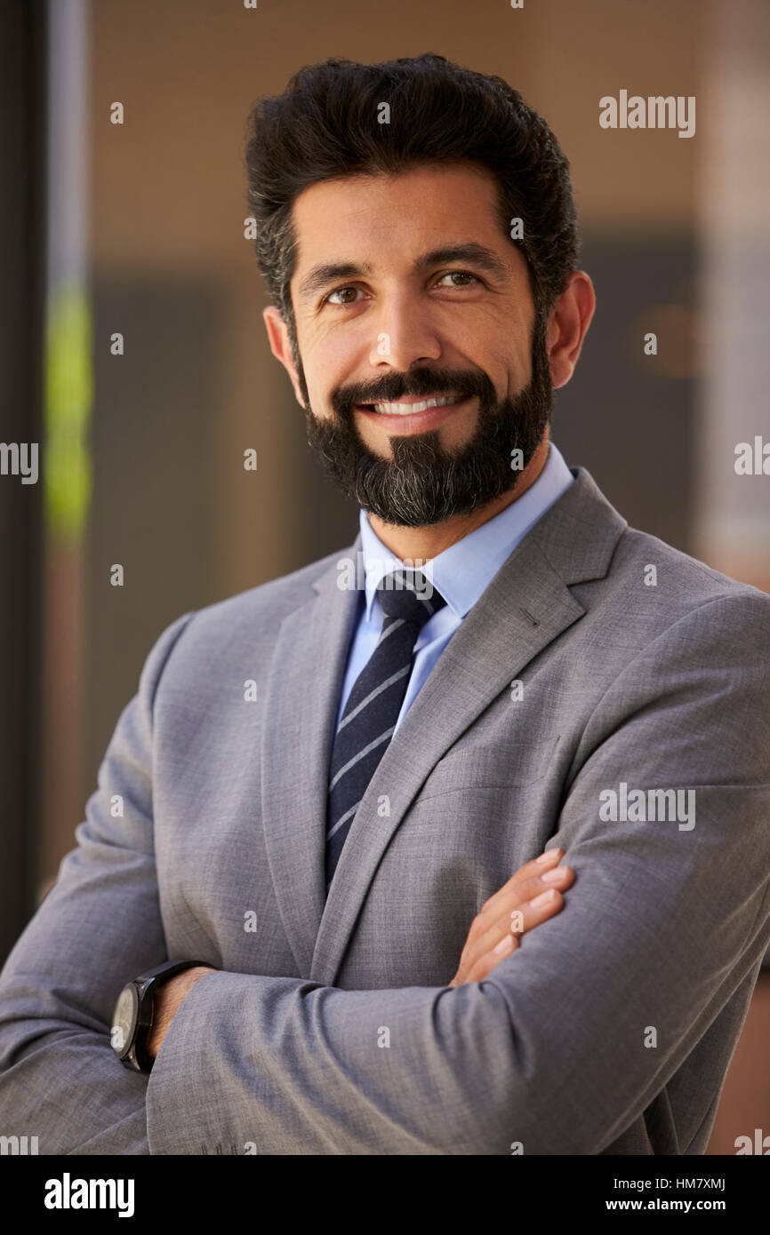 Hispanic Geschäftsmann lächelnd, Nahaufnahme Arme verschränkt, vertikal Stockfoto