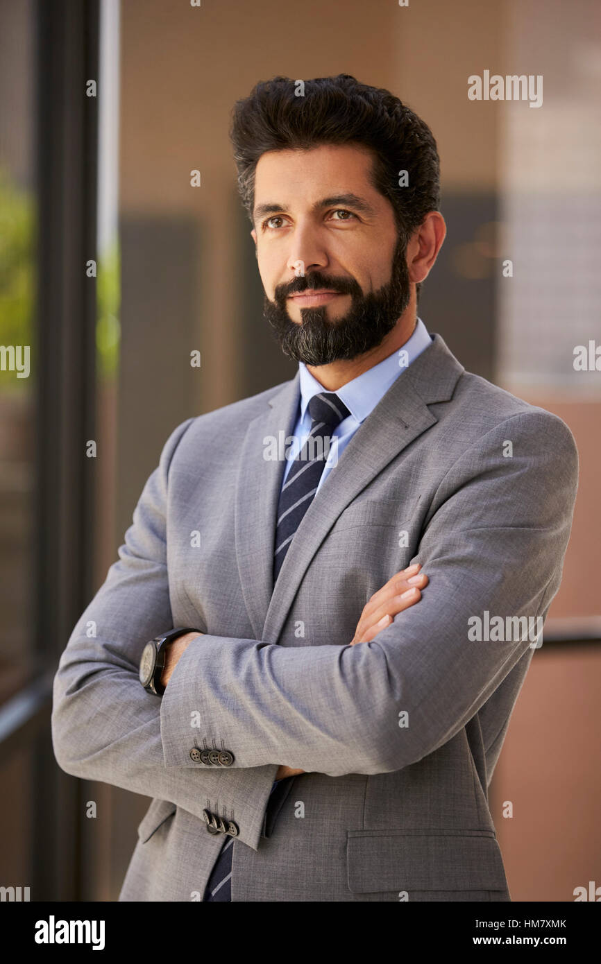 Hispano-Amerikaner Geschäftsmann mit verschränkten Armen schaut Weg, vertikale Stockfoto