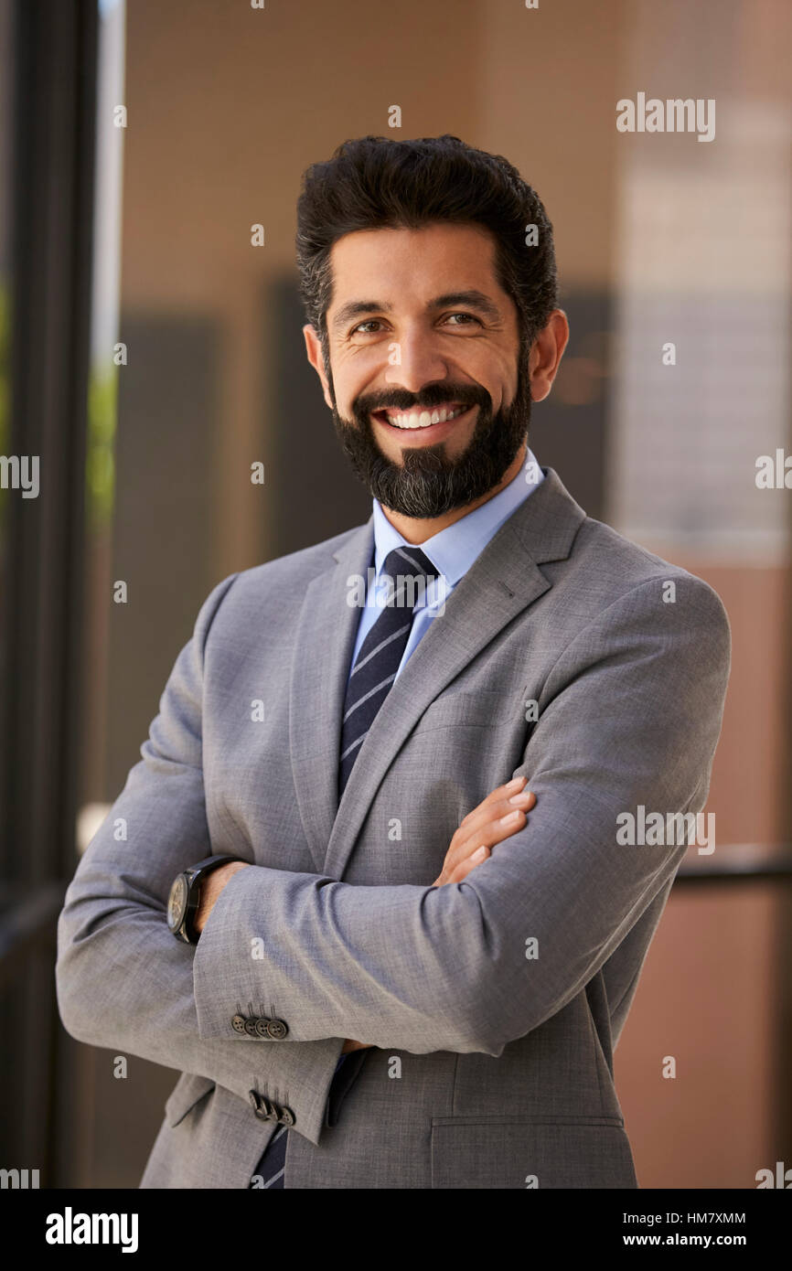 Lächelnd Hispanic Geschäftsmann mit Arme gekreuzt, vertikale Stockfoto