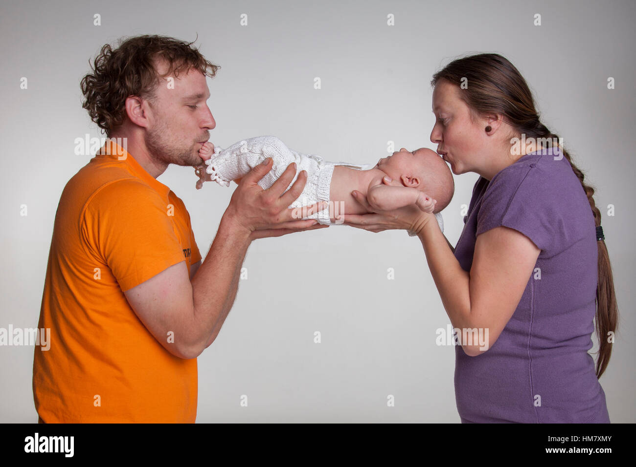 Familienportrait im Studio. Mann und Frau küssen Babys Füße und Kopf Stockfoto