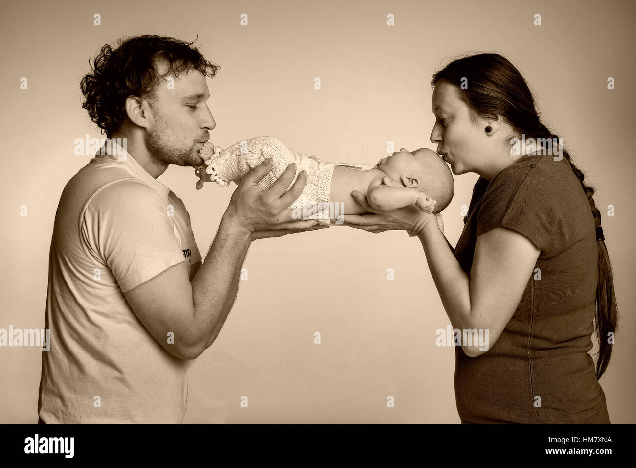 Familienportrait im Studio. Mann und Frau küssen Babys Füße und Kopf Stockfoto