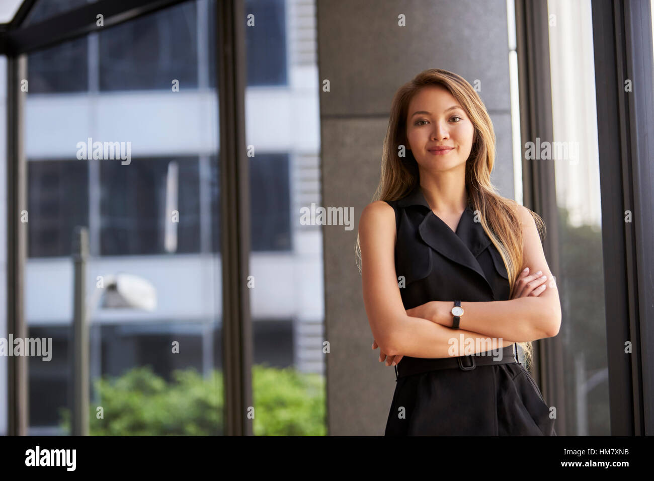 Junge asiatische Geschäftsfrau sucht, Kamera, Arme verschränkt Stockfoto