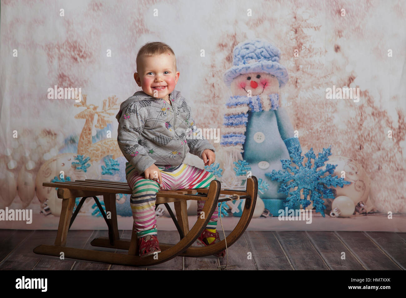 Babymädchen auf Schlitten im Winter im studio Stockfoto