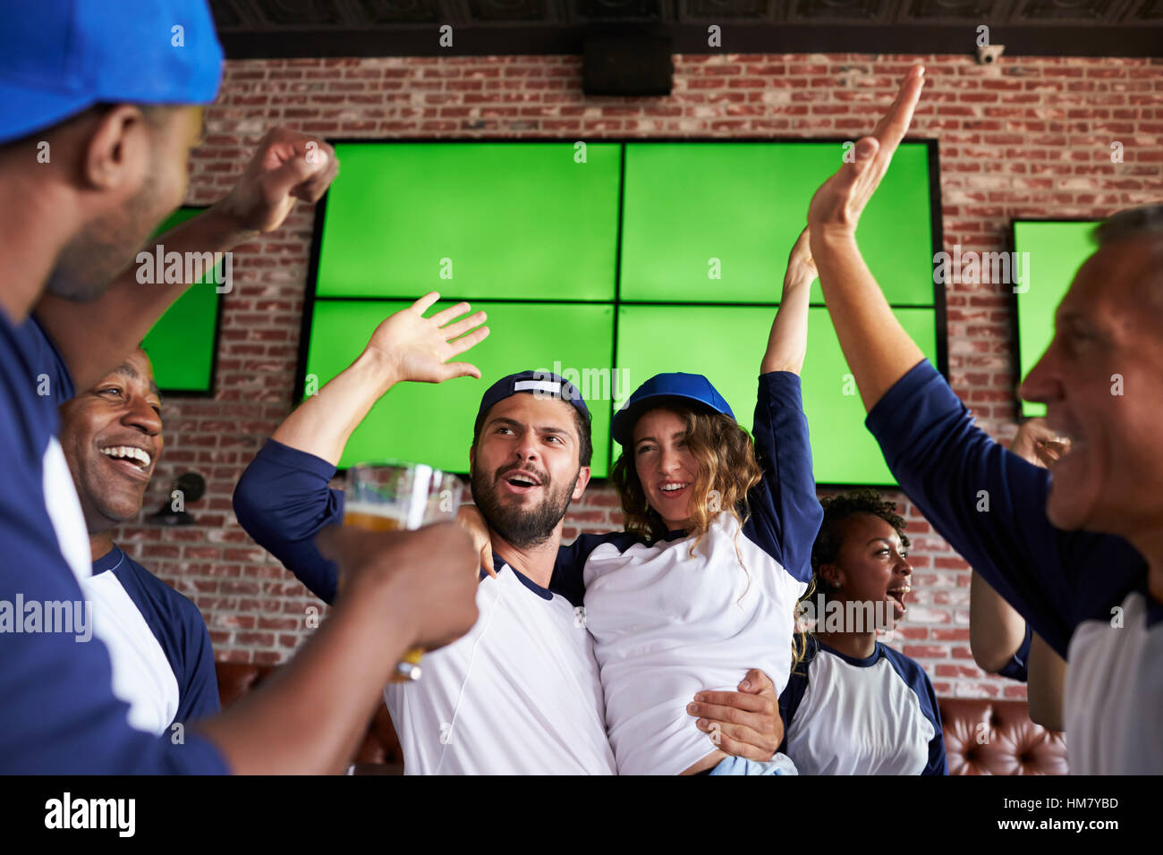 Freunde gerade Spiel Sports Bar auf Bildschirmen feiern Stockfoto