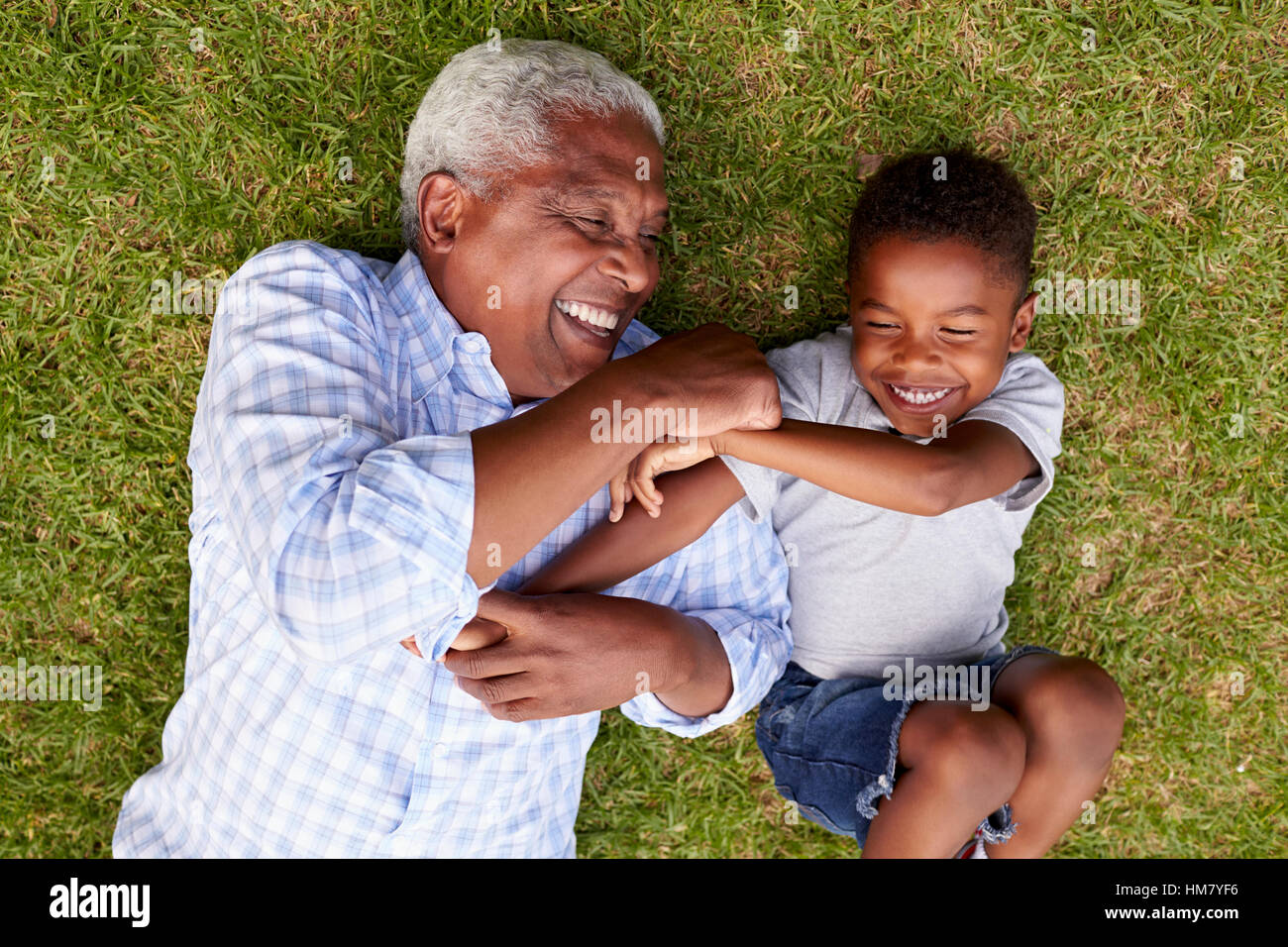 Großvater und Enkel spielen liegen auf dem Rasen, Luftbild Stockfoto
