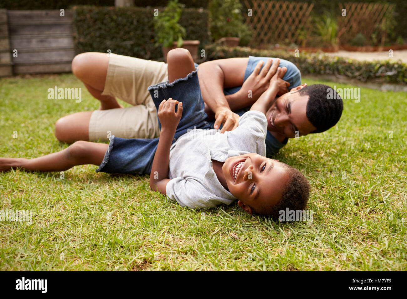 Schwarze Vater und Sohn spielen auf Rasen, niedrigen Winkel liegen Stockfoto