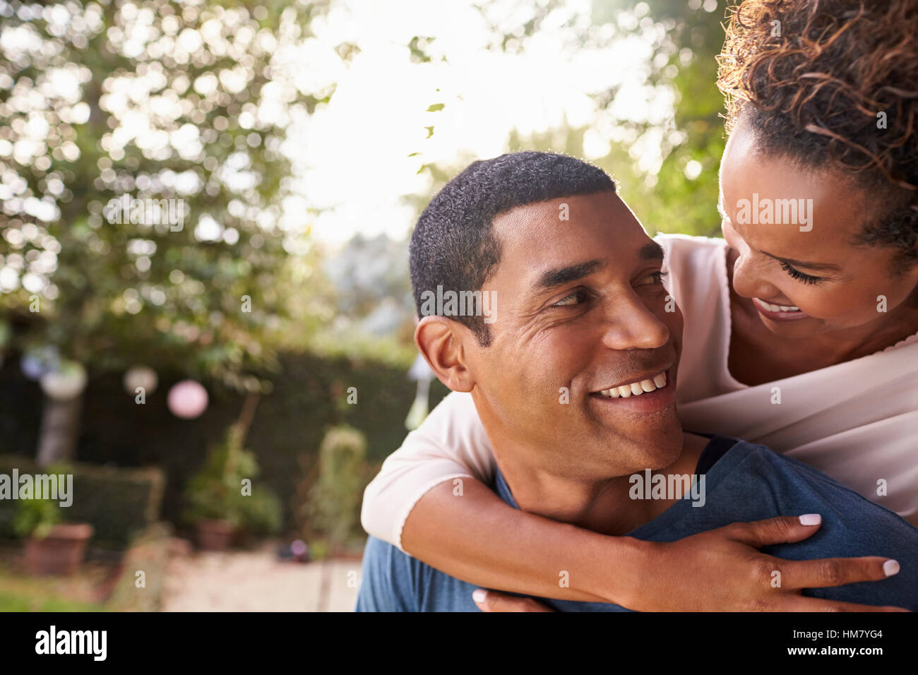 Junge schwarze paar Huckepack im Garten mit Blick auf einander Stockfoto