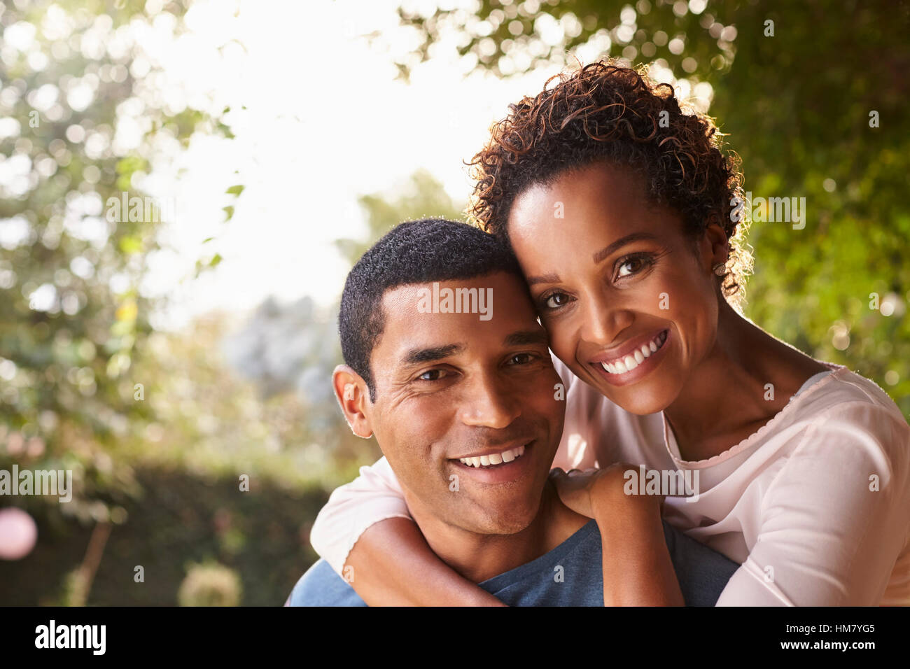 Junge schwarze paar Huckepack im Garten mit Blick in die Kamera Stockfoto
