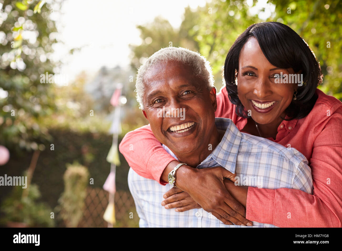 Älteres schwarzes paar Huckepack im Garten mit Blick in die Kamera Stockfoto