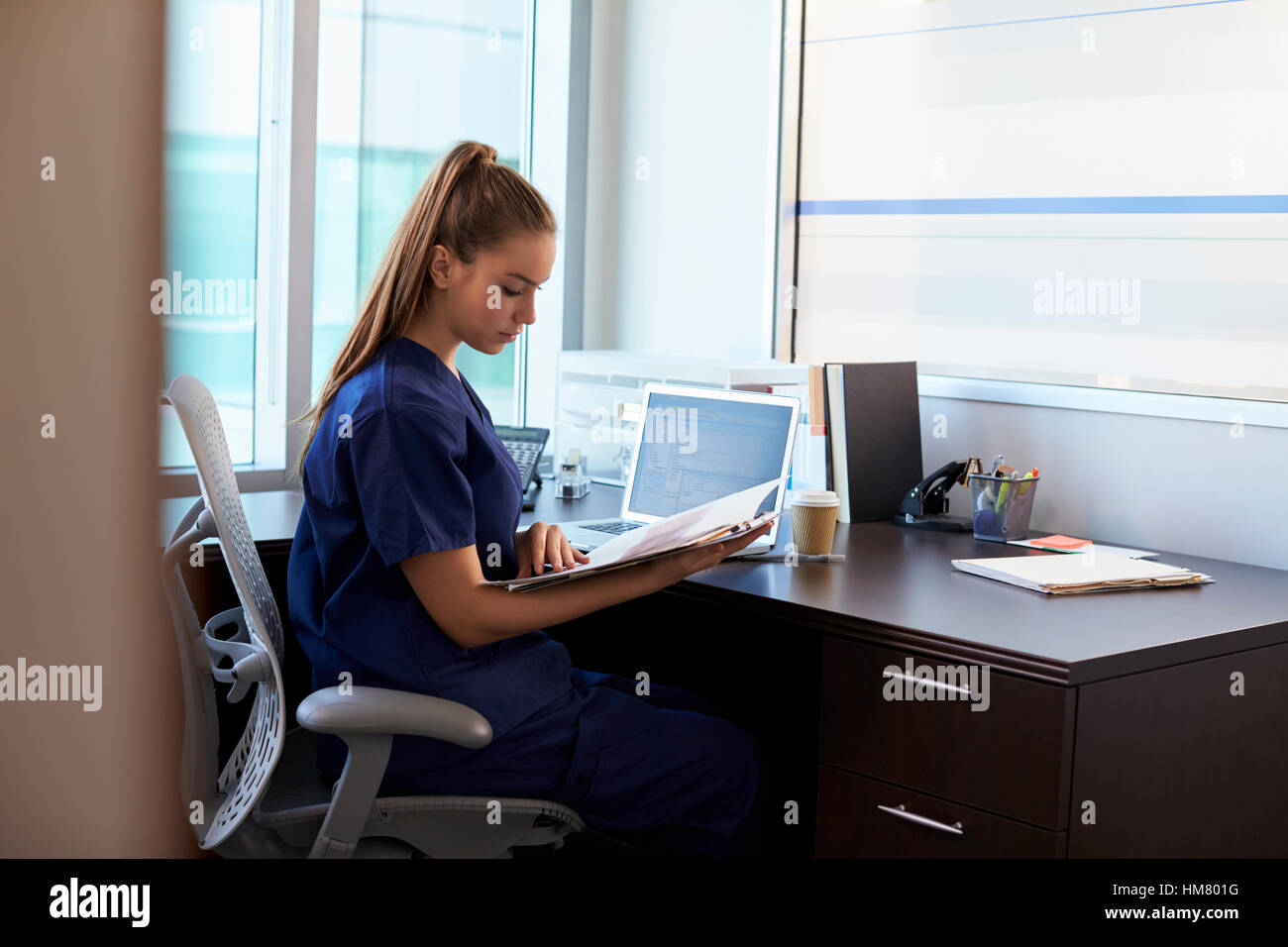 Krankenschwester, Scrubs, arbeiten am Schreibtisch im Büro tragen Stockfoto
