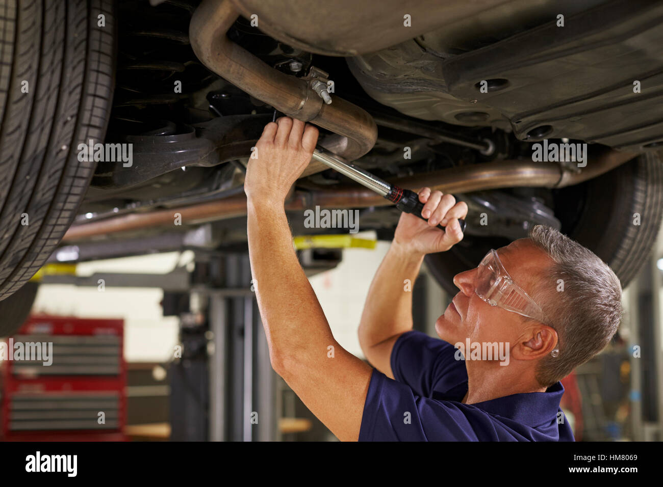 Kfz-Mechaniker arbeiten unter Auto In Garage Stockfoto