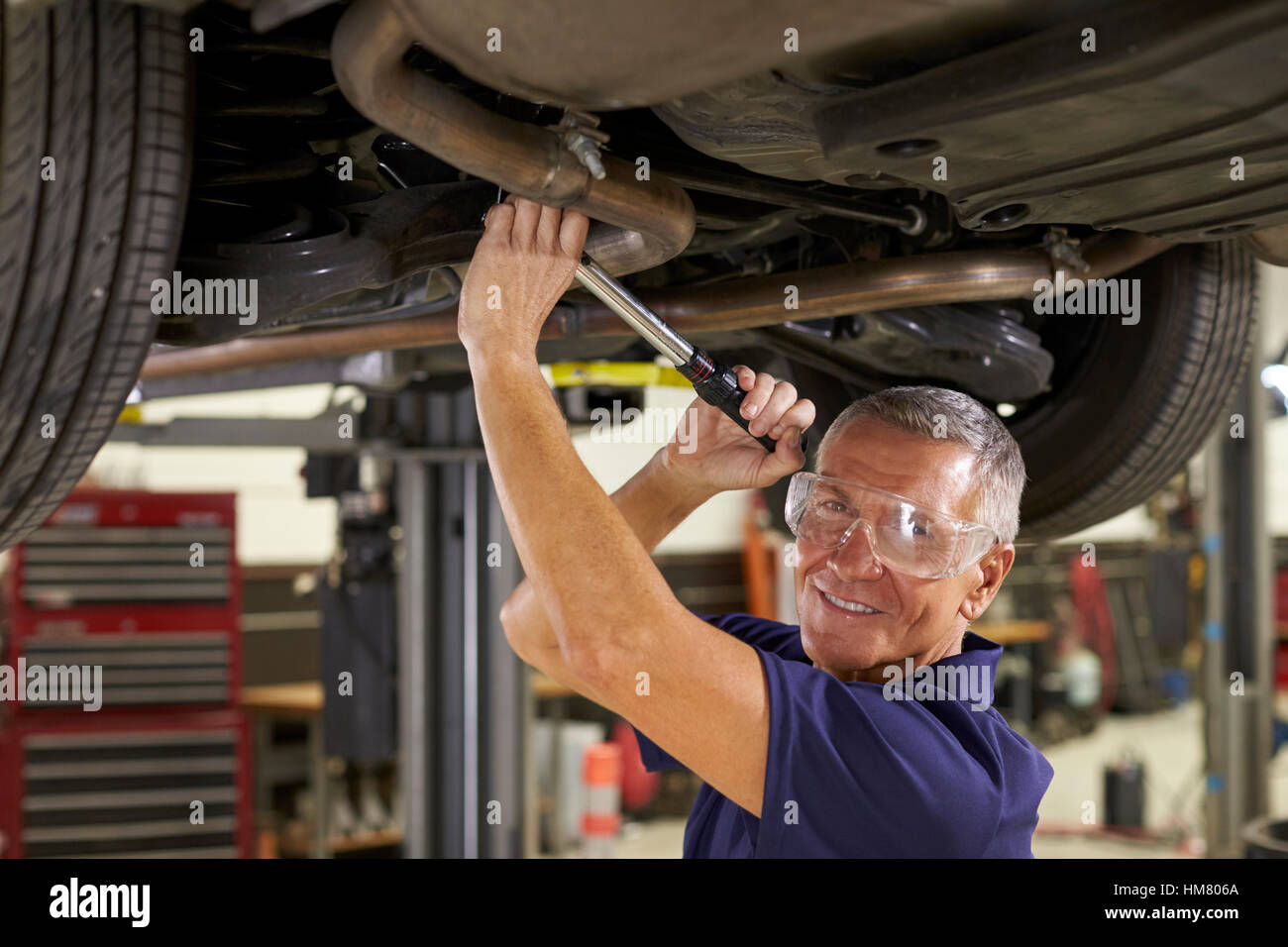 Porträt von Auto Mechaniker arbeiten unter Auto In Garage Stockfoto