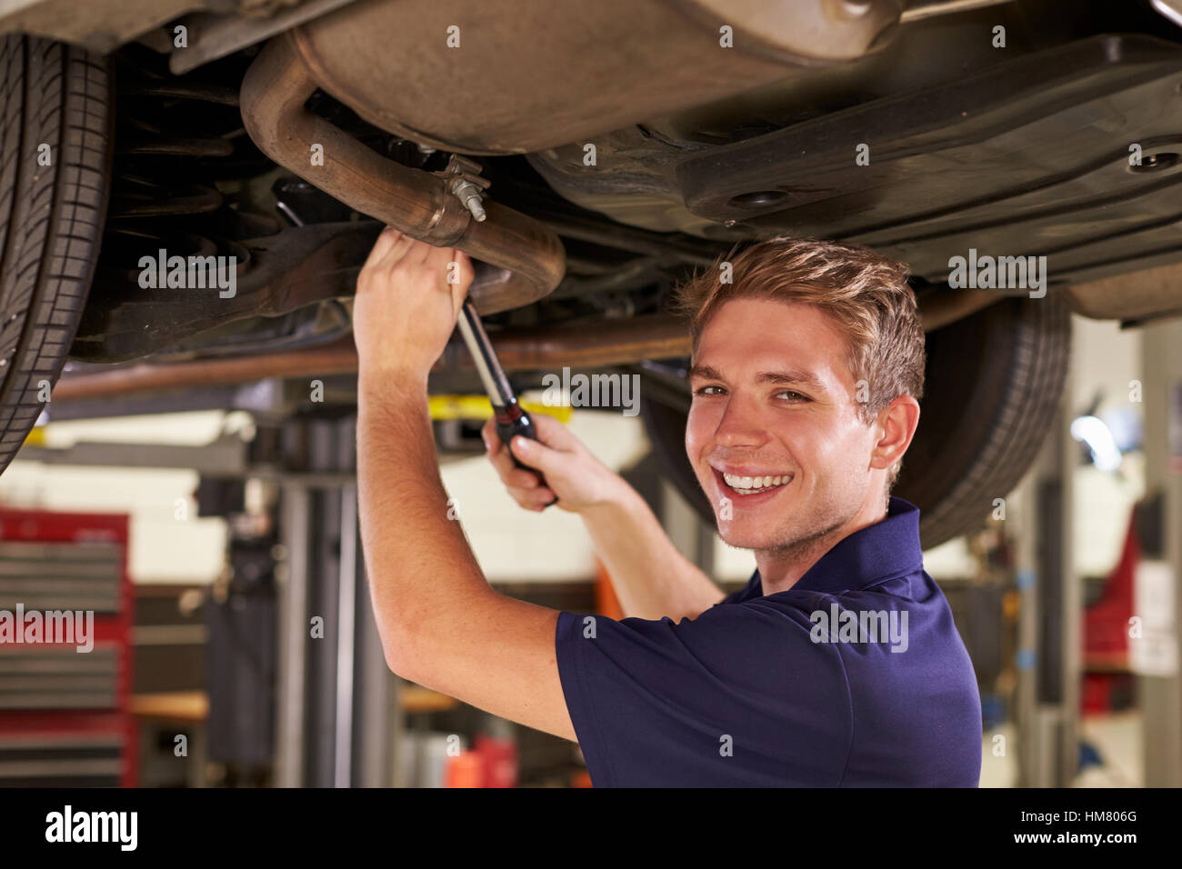 Porträt von Auto Mechaniker arbeiten unter Auto In Garage Stockfoto