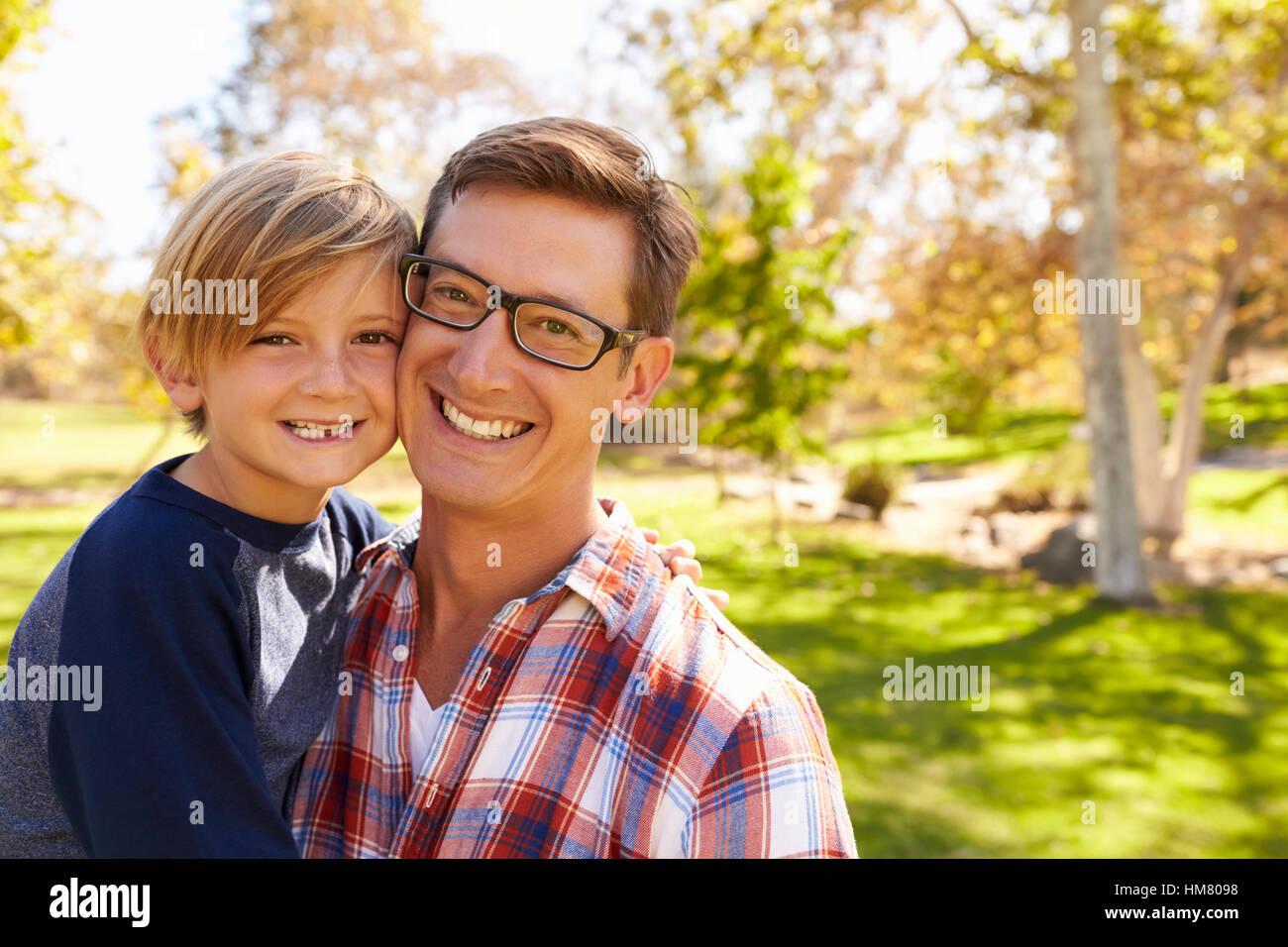 Vater und sieben Jahre alten Sohn Lächeln und Kamera in einem park Stockfoto