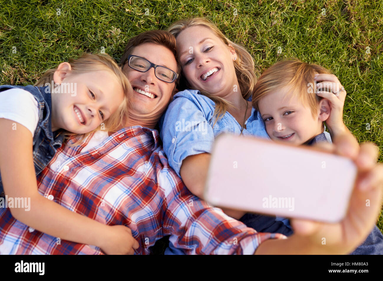 Junge weiße Familie liegen auf dem Rasen in einem Park unter einem selfie Stockfoto