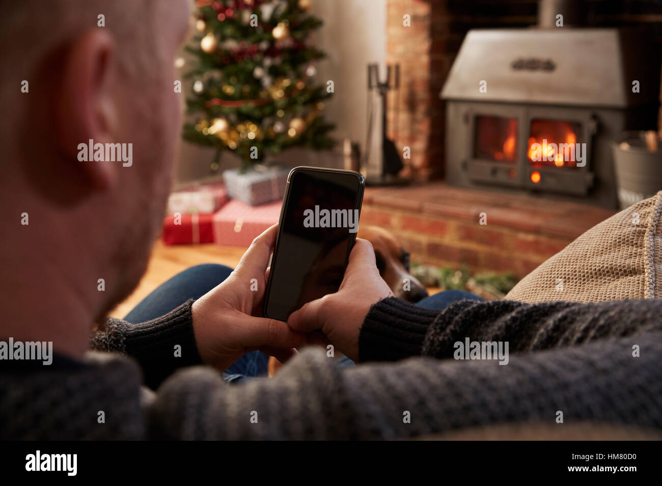 Mann mit Handy im Zimmer für Weihnachten dekoriert Stockfoto