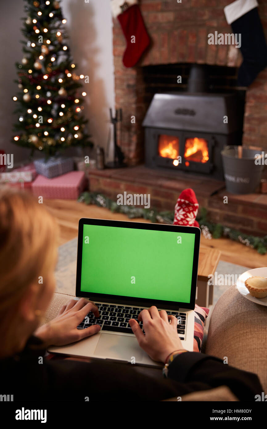 Frau mit Laptop im Zimmer für Weihnachten dekoriert Stockfoto