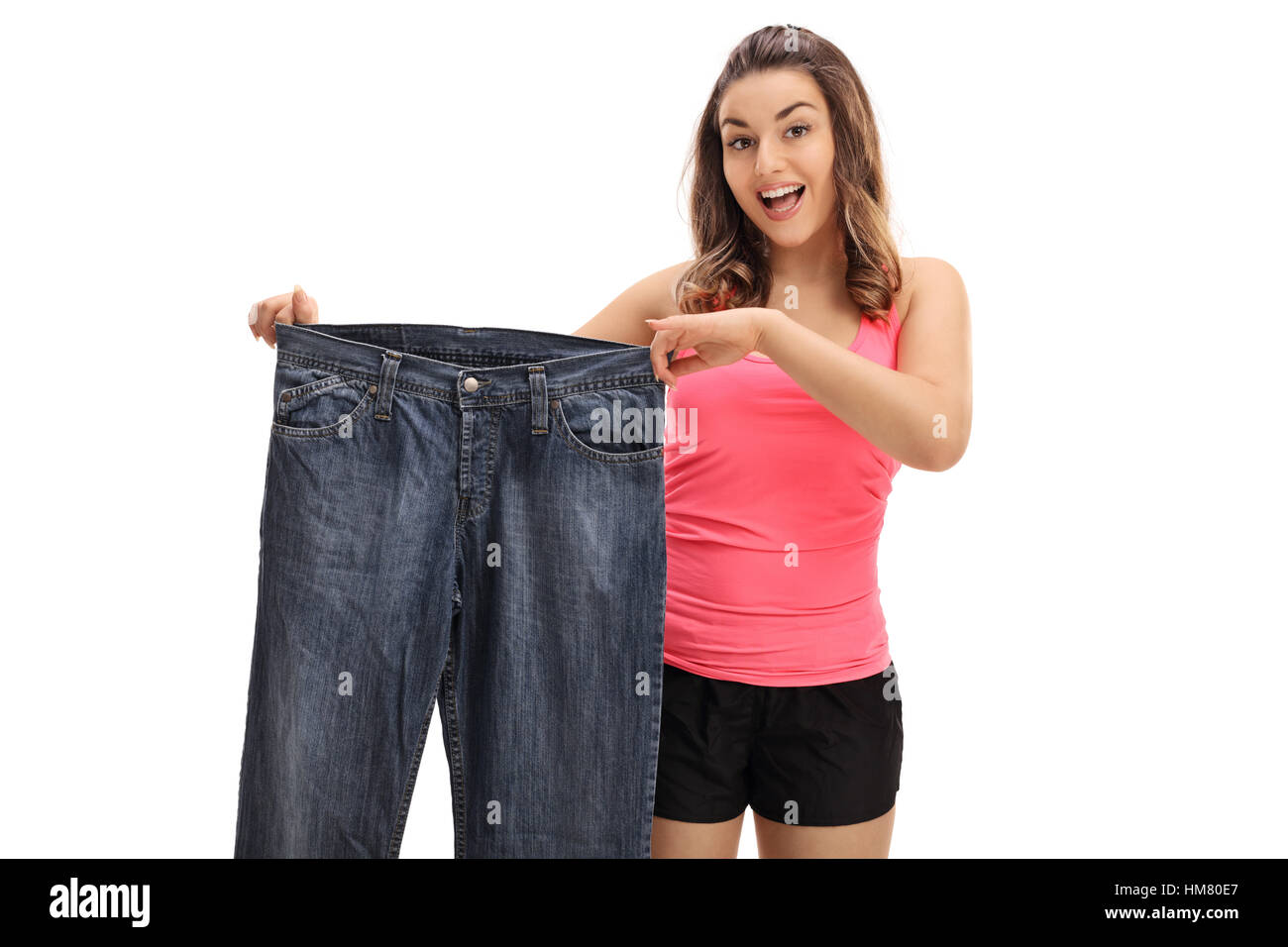 Glückliche junge Frau hält ein paar übergroße Jeans isoliert auf weißem Hintergrund Stockfoto