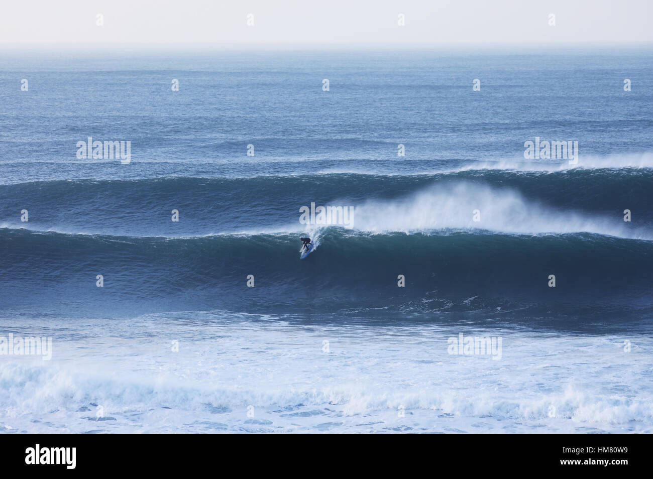 Ein Surfer reitet auf einer riesigen Welle am Cribbar Reef, Newquay Stockfoto