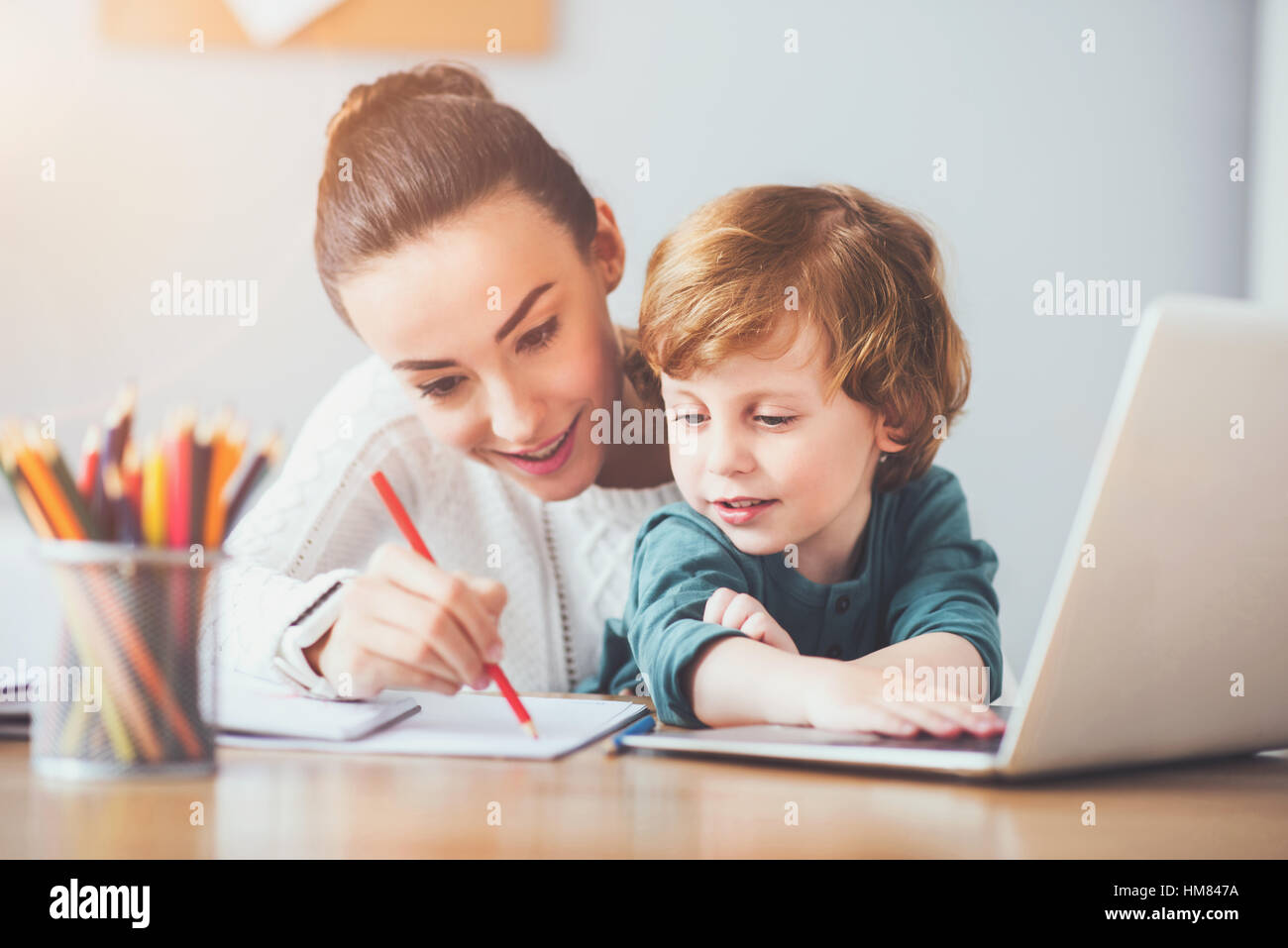 Glückliche Mutter zeigt ihrem Sohn wie Sie schreiben Stockfoto