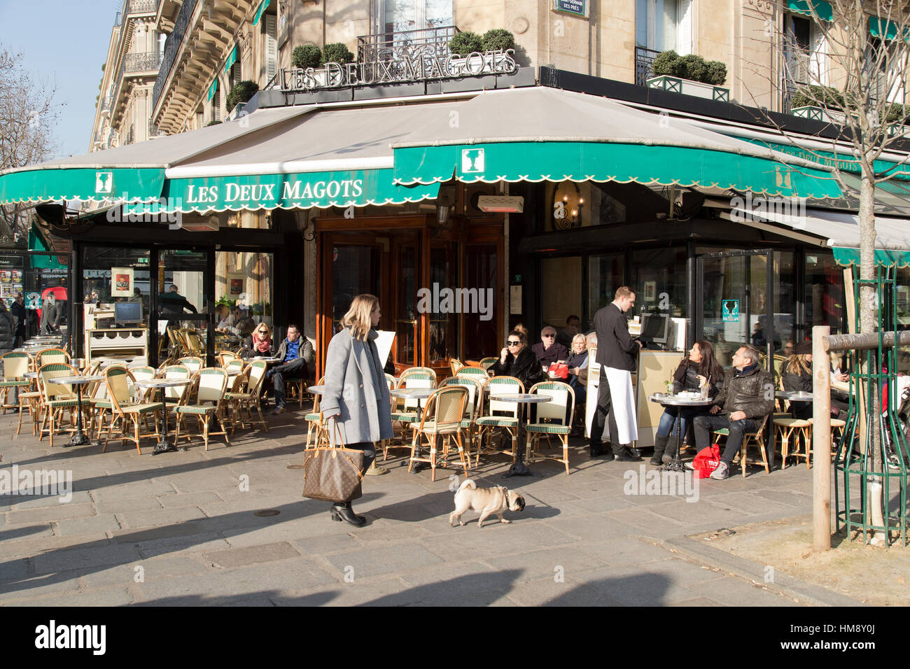 Touristen sitzen außerhalb Café Les Deux Magots in Paris Frankreich im Winter Stockfoto