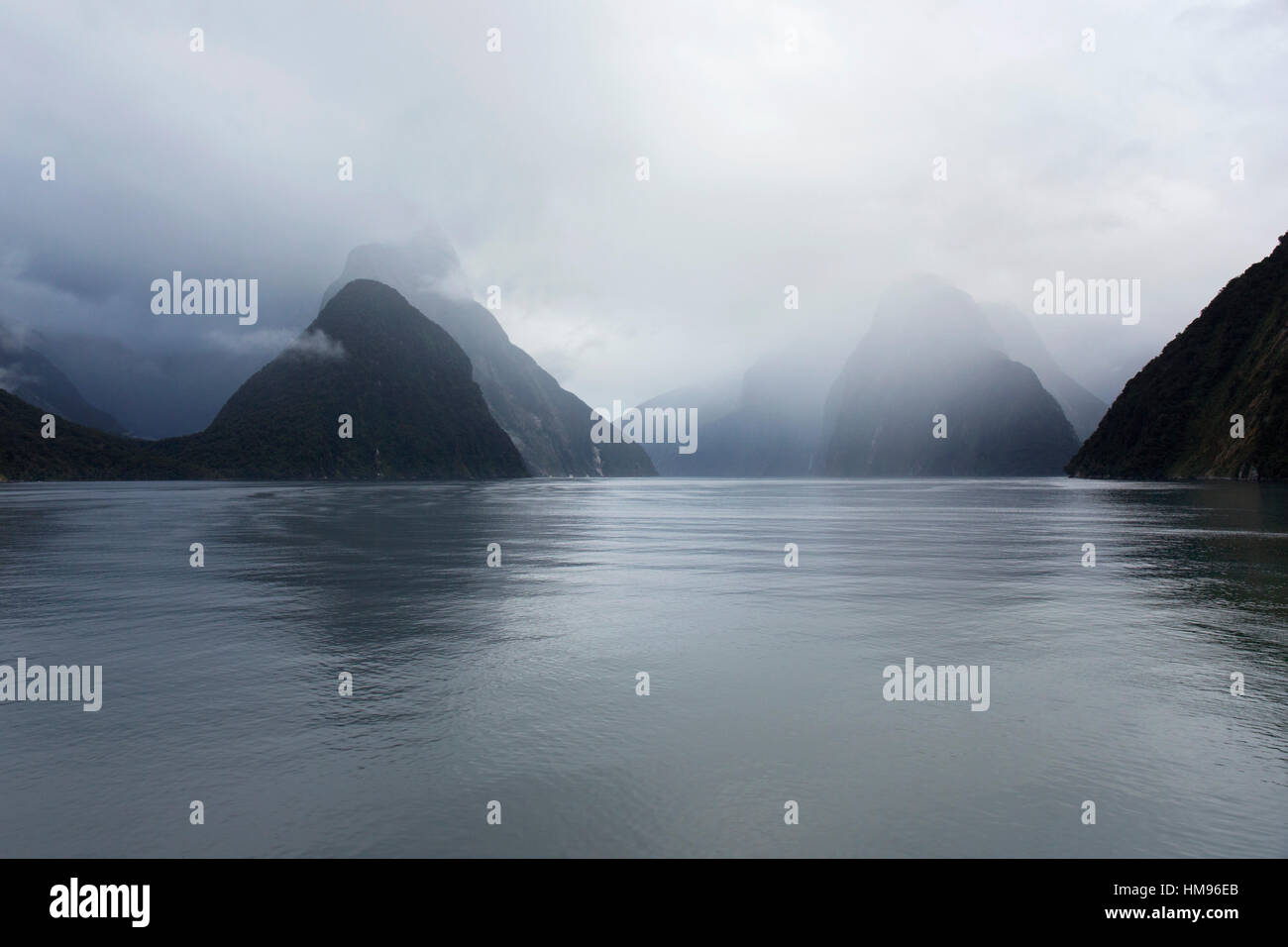 Blick nach unten regnerischen Milford Sound, Bergen verdeckt von Cloud, Milford Sound, Fiordland-Nationalpark, Southland, Neuseeland Stockfoto