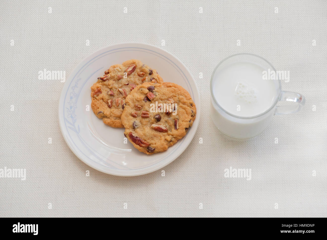 Zwei warme, frische Pecan Schokoladenkekse auf eine Untertasse mit einer Tasse Milch. Studio im Haus. USA. Stockfoto