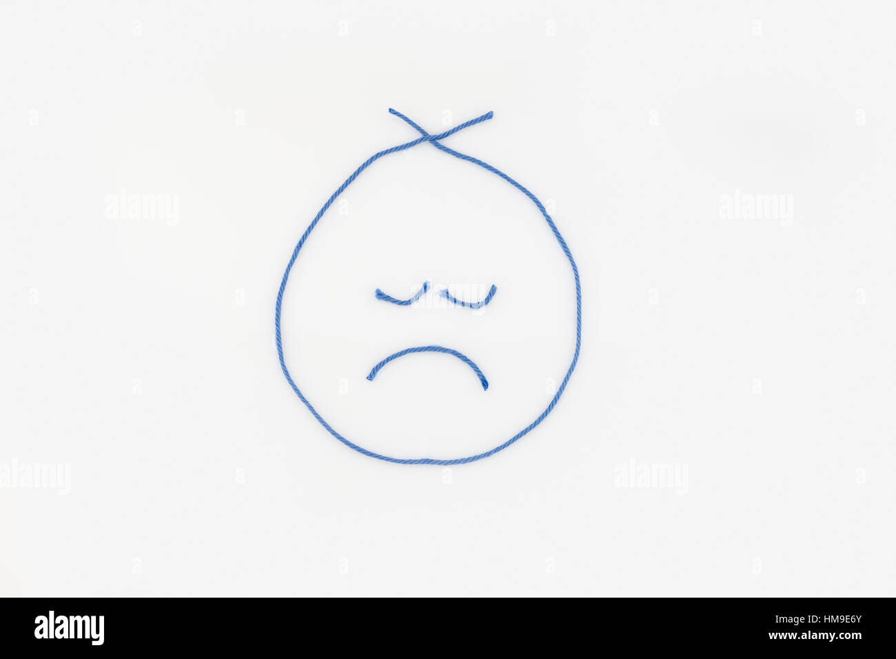 Ein trauriges Gesicht, geprägt vom blauen Garn. auf einem weißen Hintergrund. Ausschnitt. Abbildung. Konzept, konzeptionelle. Stockfoto