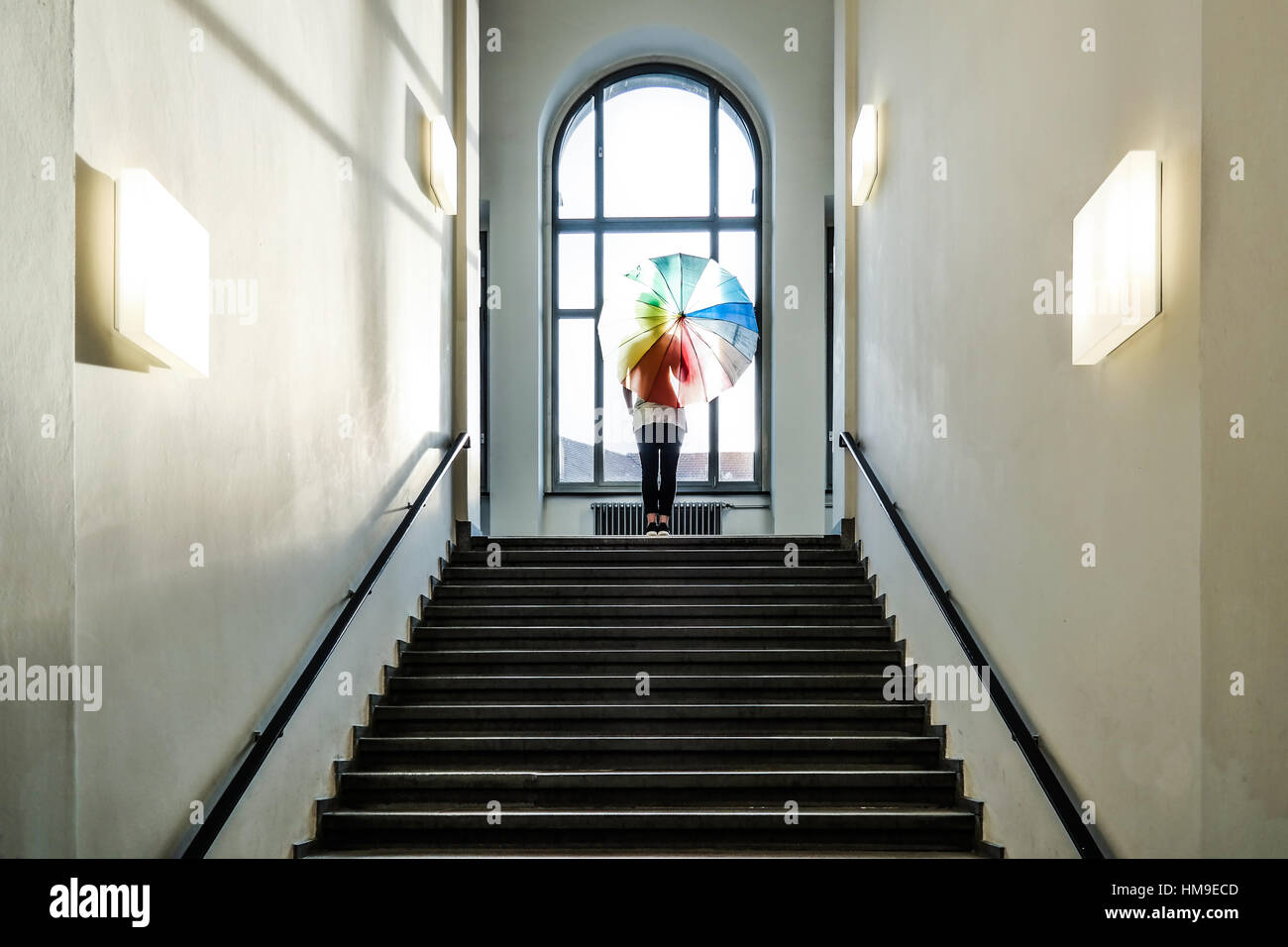 Weibchen mit Regenbogen farbige Dach stehen an der Spitze der Treppe vor Fenster Stockfoto